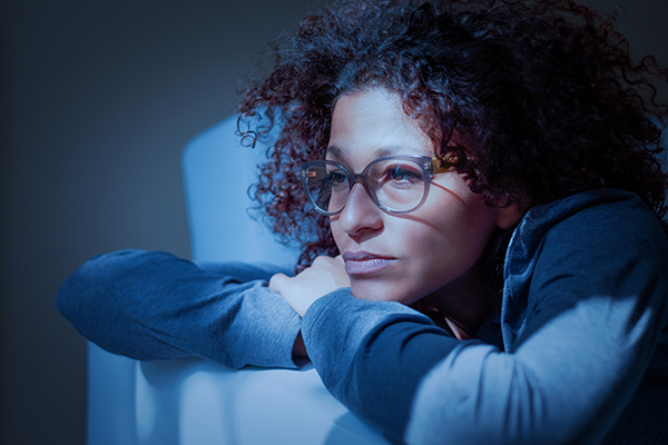 Worried black woman leaning on side of couch looking worried