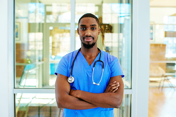 Black man wearing blue scrubs with stethoscope around his neck
